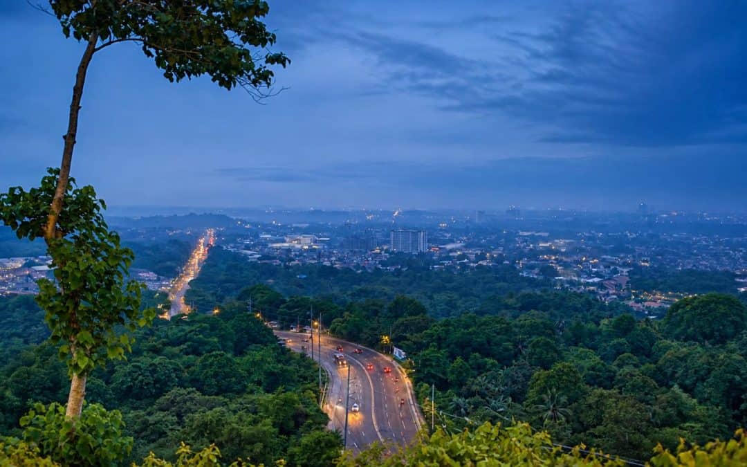 Davao City and a winding road viewed from the surrounding green highlands at dusk