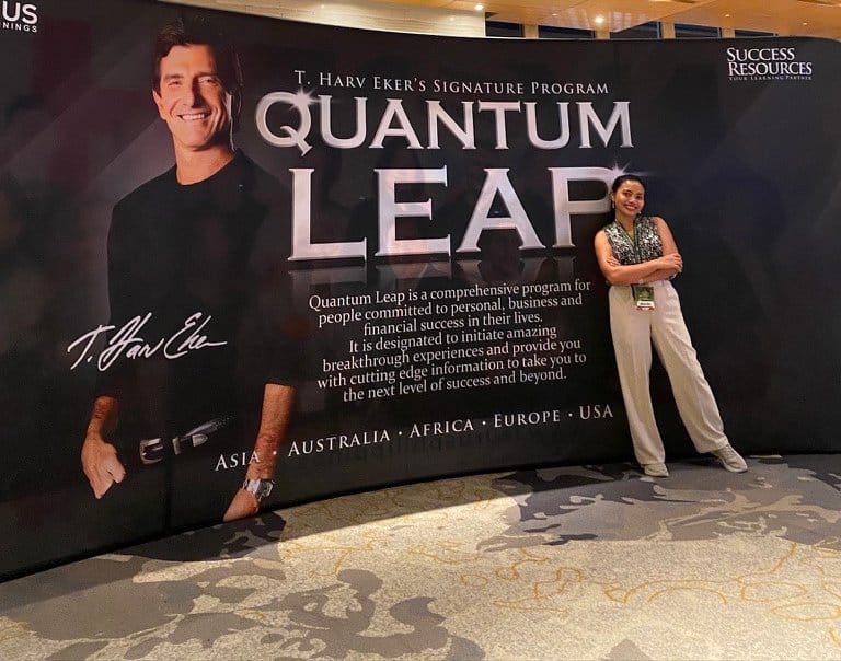 An attendee stands beside a Quantum Leap programme banner in an indoor venue.